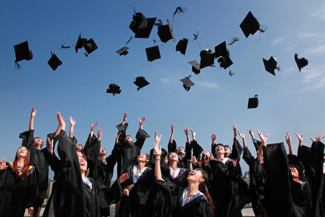 Graduating students tossing mortar boards in the air