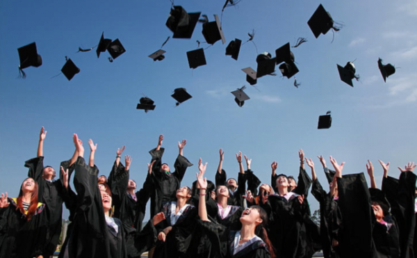 Graduating students tossing mortar boards in the air